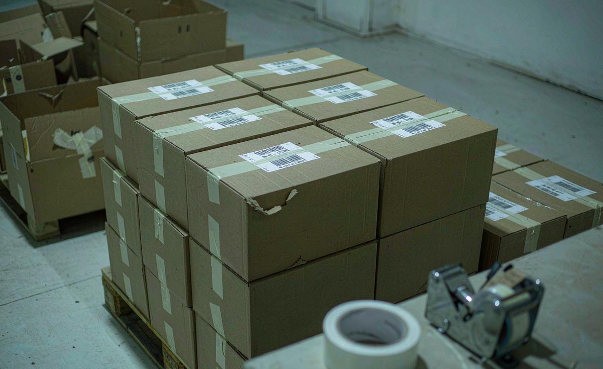 Packing bench laid out with folded custom bags, polybags, desiccant sachets, barcode labels and a sealed master carton ready for dispatch