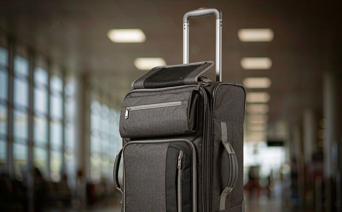 A charcoal cabin bag with a trolley sleeve standing beside a suitcase handle