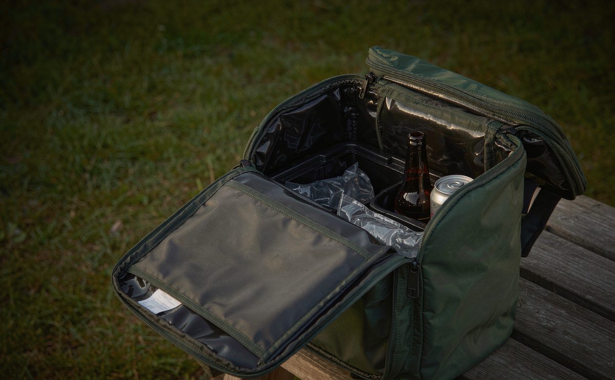 A dark green soft cooler bag open to show ice packs and drink cans
