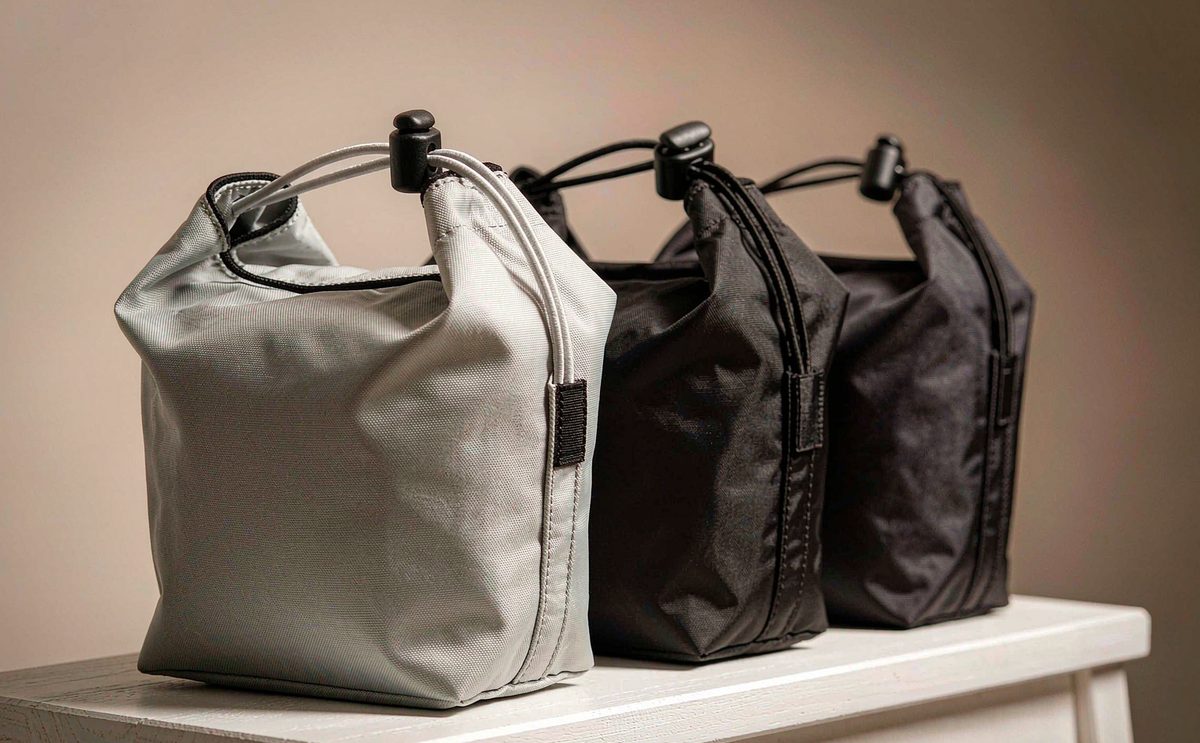 Three drawstring bags in natural cotton and black nylon with cord locks