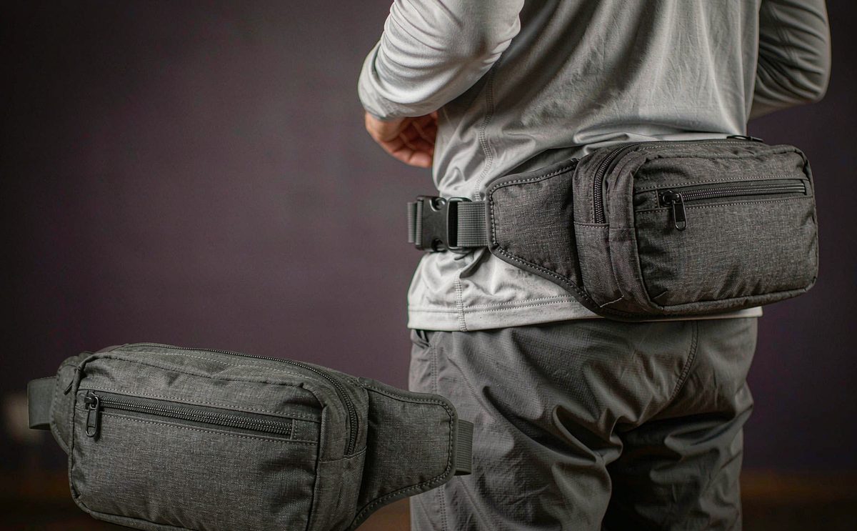 A charcoal waist pack with a low-profile buckle worn on the hip