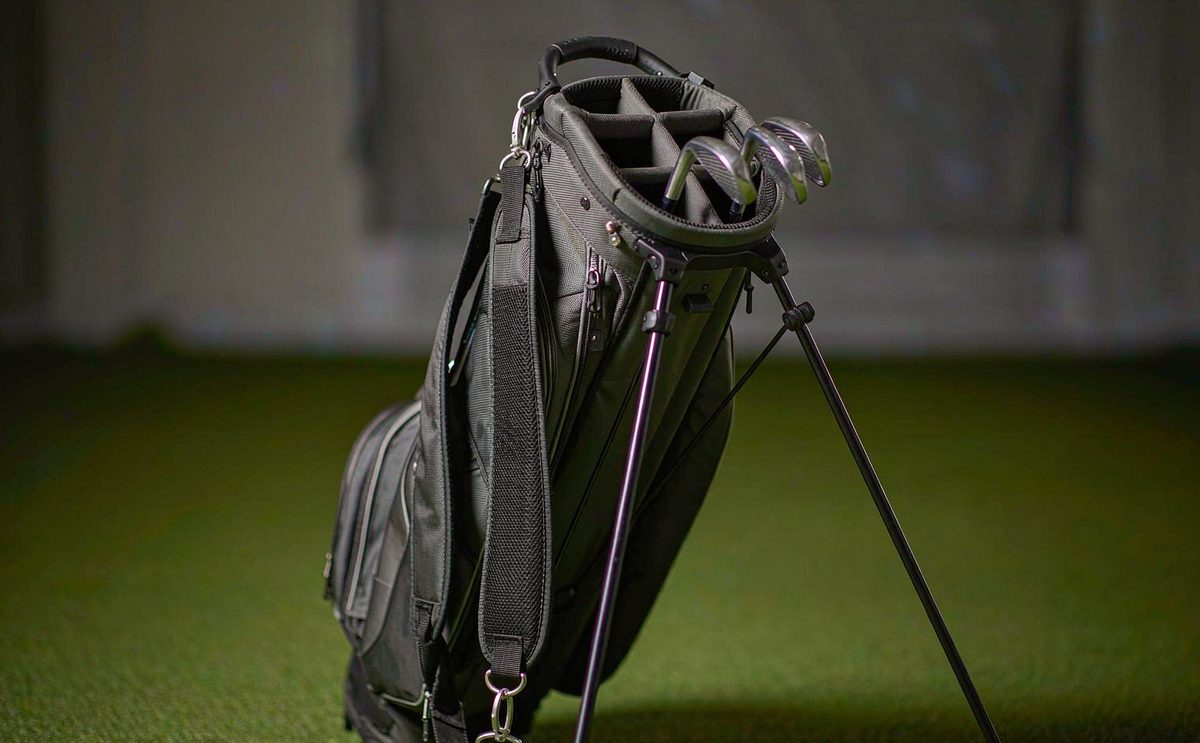 A black and grey stand golf bag with divided club slots on a putting green