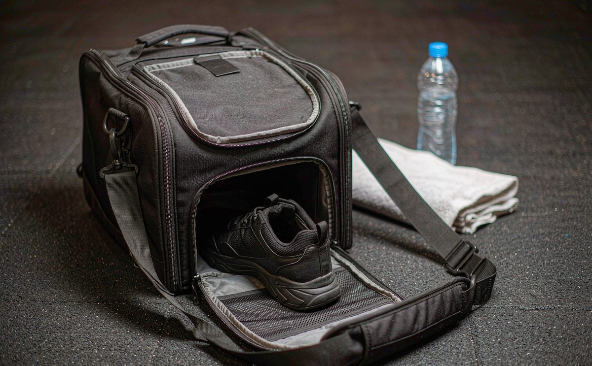 Custom gym bag sample opened on a studio table showing a vented shoe bay and a lined wet-kit pocket