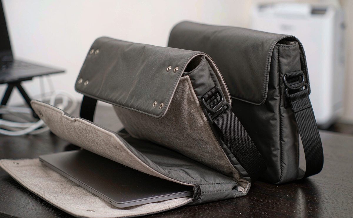 A slim nylon laptop sleeve open on a desk with a laptop sliding into it