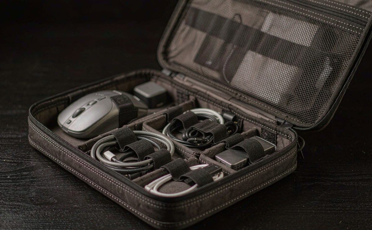 An open tech organizer pouch with elastic loops holding cables and a power bank
