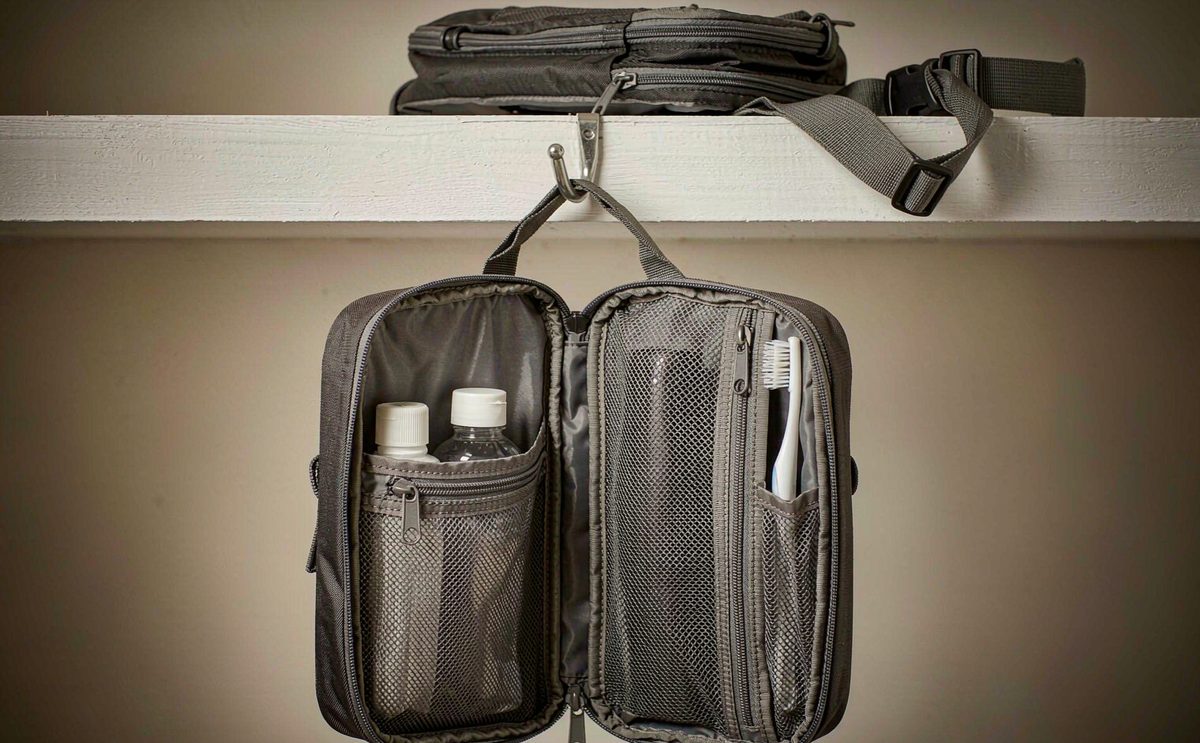 A hanging toiletry bag unzipped from a hook with mesh pockets holding bottles